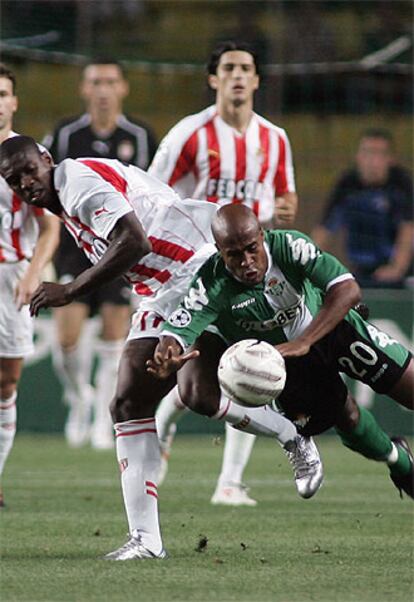 Marcos Dos Santos del Betis lucha por el balón con Olivier Kapo.