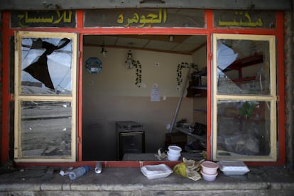 Recipientes de comida para llevar en el alféizar de una tienda dañada por la guerra.