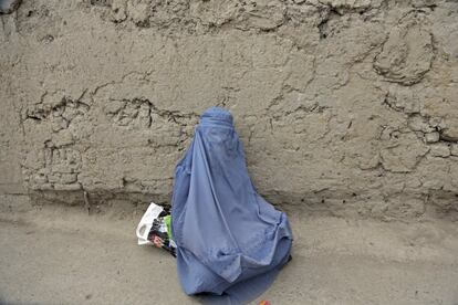 Una mujer sentada en la carretera espera las donaciones de los transeúntes en Kabul (Afganistán).