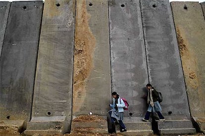 Dos niñas palestinas circulan cerca de Ramala ante el muro de separación levantado por Israel.