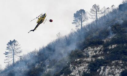 Un helicóptero realiza una maniobra para arrojar agua sobre eln incendio forestal en Barx, el 7 de agosto.