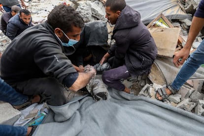 Ciudadanos palestinos trabajan para rescatar el cadáver de un niño de entre los escombros de un edificio destruido por ataques israelíes en Rafah este viernes.