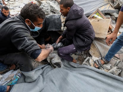 Ciudadanos palestinos trabajan para rescatar el cadáver de un niño de entre los escombros de un edificio destruido por ataques israelíes en Rafah este viernes.