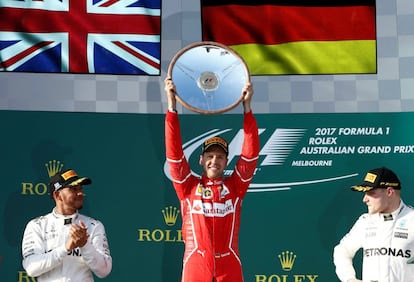 El piloto Sebastian Vettel (c) de la escudería Ferrari celebra su victoria en el pódium junto con Lewis Hamilton (izquierda) y Valtteri Bottas, en segunda y tercera posición.