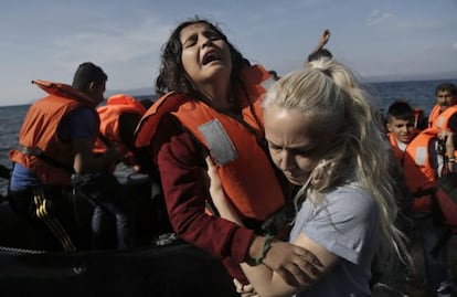Una ni&ntilde;a siria llora mientras es ayudada por una voluntaria a su llegada en lancha a la isla de Lesbos