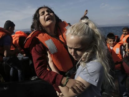 Una ni&ntilde;a siria llora mientras es ayudada por una voluntaria a su llegada en lancha a la isla de Lesbos