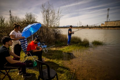 Cuatro amigos pescan en el embalse, frente a los edificios abandonados de la central nuclear de Valdecaballeros.