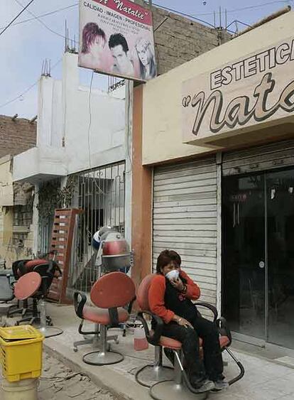 Una mujer se protege con una mascarilla a las puertas de una peluquería.