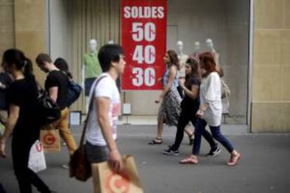 Un grupo de personas pasean frente a una tienda en rebajas, en París. EFE/Archivo