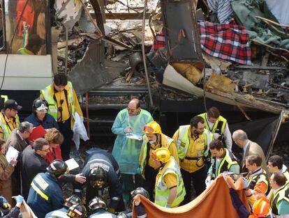 Bomberos y personal sanitario examinan varios cad&aacute;veres entre los restos de uno de los vagones de la estaci&oacute;n de Atocha.