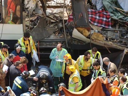 Bomberos y personal sanitario examinan varios cad&aacute;veres entre los restos de uno de los vagones de la estaci&oacute;n de Atocha.