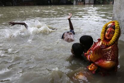 Niños nadan en una corriente tras las lluvias del monzón en Calcuta, India.