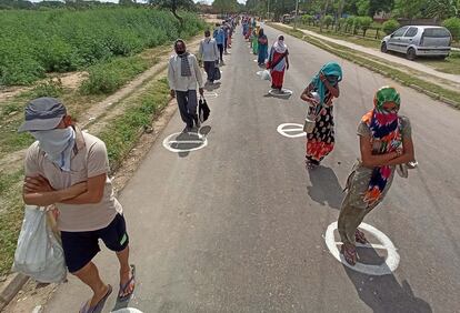 Vecinos de Kajheri Village, India, mantienen la distancia social mientras esperan a que repartan comida.