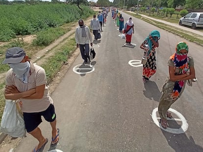 Vecinos de Kajheri Village, India, mantienen la distancia social mientras esperan a que repartan comida.