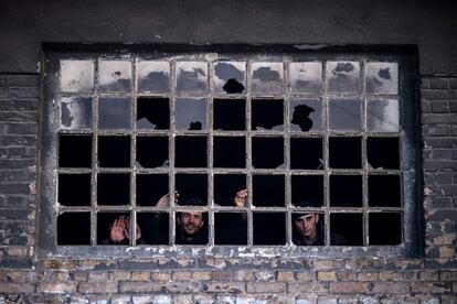 Un grupo de migrantes observa a través de una ventana sin cristales de un edificio abandonado en Belgrado (Serbia).