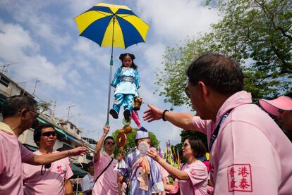 Una niña vestida como deidad subida a un pedestal participa en un desfile durante el festival del bollo de Cheung Chau en Hong-Kong.
