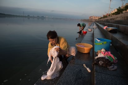 Mulheres chinesas lavam suas roupas no rio, próximo da Ponte da Amizade Sinocoreana, em Dandong.