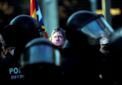 Policía antidisturbios durante una manifestación independentista en apoyo a Puigdemont, en la que se han llevado caretas del candidato como símbolo de apoyo.