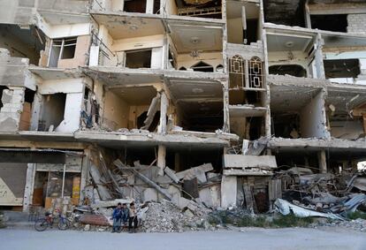 Unos niños sirios permanecen sentados frente a un edificio prácticamente destruido en el pueblo rebelde de Erbin, en la región este de Ghouta, a las afueras de Damasco (Siria).