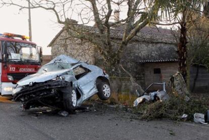 Un camión de bomberos, junto al vehículo destrozado cuyo conductor, un joven de 20 años, murió el domingo al salirse de la vía y estrellarse contra un muro en la carretera de Tomiño a Pinzás.