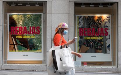 Una mujer pasa frente a un escaparate en el que se anuncia el inicio de las rebajas, este miércoles en Madrid.