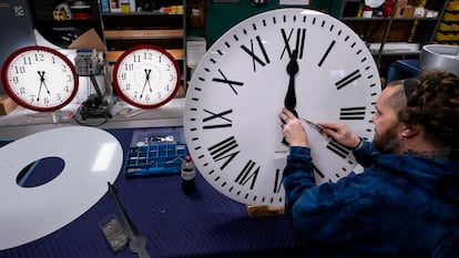 Ian Roders ajusta las manecillas de un reloj en Electric Time Company, el martes 1 de noviembre de 2022, en Medfield, Massachusetts.