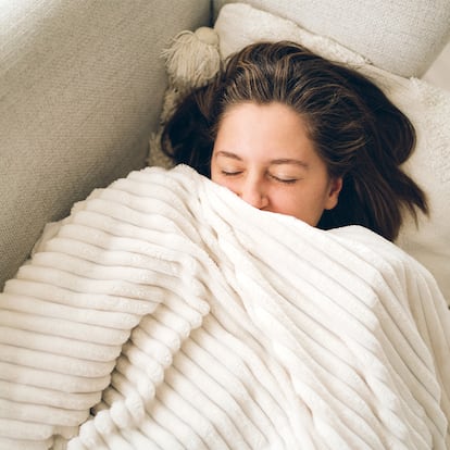 Una chica en el sofá de su casa con una manta extragrande.