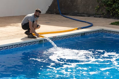 Un trabajador de una empresa de camiones cisterna llena la piscina de una urbanización de Rincón de la Victoria, Málaga.