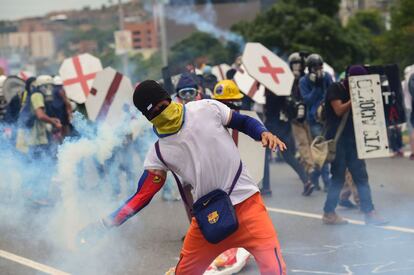 Un opositor al Gobierno de Maduro lanza un bote de humo a las fuerzas policiales durante las protestas de Caracas (Venezuela).