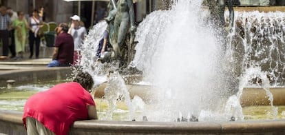 A woman cools down in a fountain in Valencia’s Plaza de la Virgen.