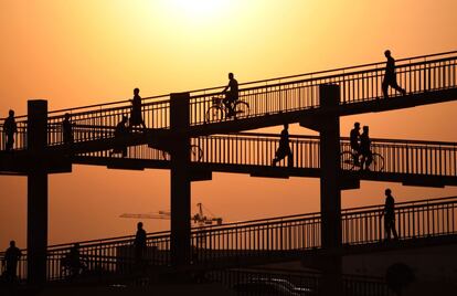 Trabajadores asiáticos cruzan un puente peatonal en Dubai (Emiratos Árabes Unidos) mientras se dirigen a trabajar en un mercado de verduras, este miércoles.