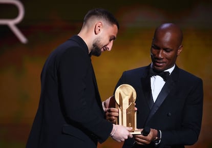 El italiano Gianluigi Donnarumma, del PSG, recibe el Trofeo Yashin al mejor portero de manos de Didier Drogba.