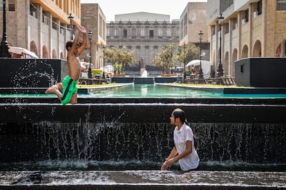 Un joven y su hermano pequeño se bañan en una fuente en la Plaza Tapatía (Guadalajara), para refrescarse, este 9 de mayo.