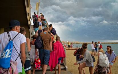 Ba&ntilde;istas saliendo de la playa de la Barceloneta por alerta de tormenta.