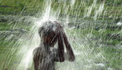 Un niño utiliza un grifo de la calle para refrescarse en medio del aumento de las temperaturas en la India.