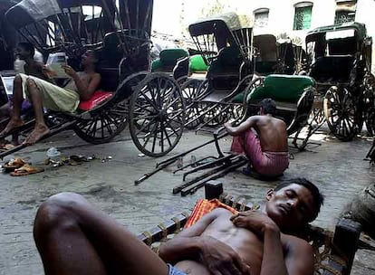 Un conductor de <i>rickshaw</i> descansa mientras sus compañeros esperan nuevos clientes. Los <i>rickshaw</i> han sido prohibidos y desaparecerán este año de Calcuta.