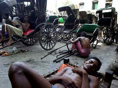 Un conductor de <i>rickshaw</i> descansa mientras sus compañeros esperan nuevos clientes. Los <i>rickshaw</i> han sido prohibidos y desaparecerán este año de Calcuta.