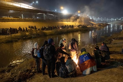 Venezuelan migrants warm by a fire after hundreds of other migrants surged across the Rio Grande into El Paso, Texas, to seek asylum on December 19, 2022, as seen from Ciudad Juárez, Mexico.