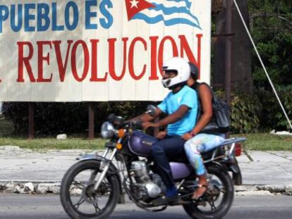 Motociclistas passam por cartaz alusivo à revolução cubana, em Havana.