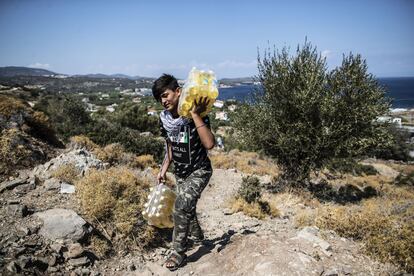 Un joven carga con varias botellas. Al fondo, la costa de Lesbos. Solamente 24 kilómetros separan la isla de la costa turca.