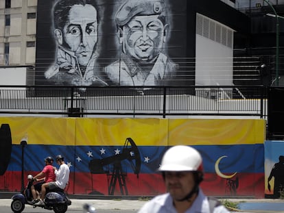 A motorcycle passes in front of a mural of Simón Bolívar and Hugo Chávez in Caracas, in an image from 2022.