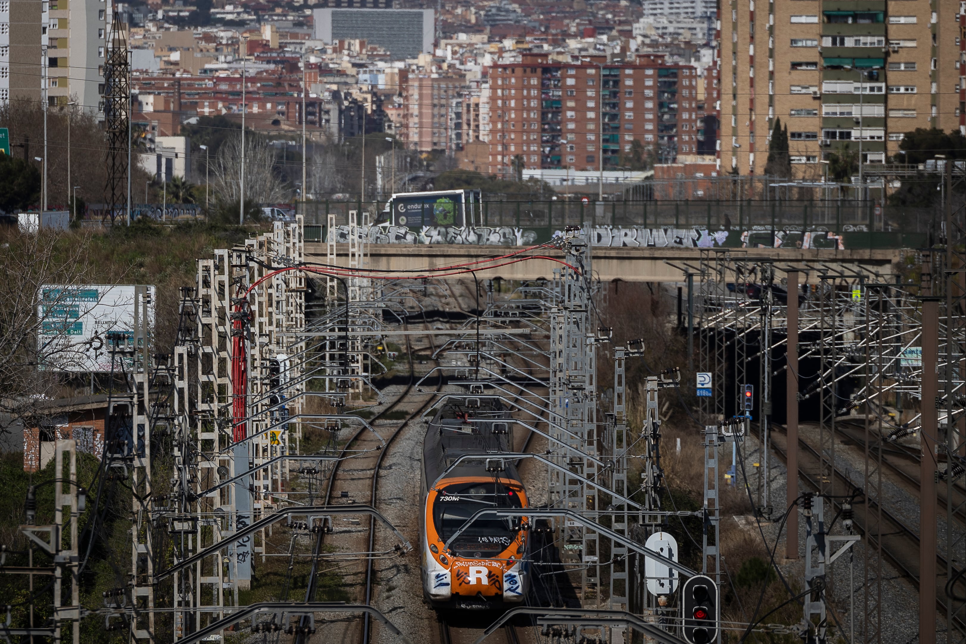 Un tren de Rodalies (Cercanias) Renfe de la linia R2 circula por las vías del tren a su paso por la Zona Franca, de fondo, en una imagen de archivo.