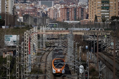 Un tren de Rodalies Renfe de la linia R2 circula por las vas del tren a su paso por la Zona Franca, de fondo, la Area Metropolitana de Barcelona.