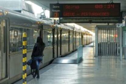 Una mujer aguarda junto a un tren parado mientras un panel electrónico advierte de la huelga general y de disturbios en la estación de Cais do Sodre en Lisboa, Portugal. EFE/Archivo