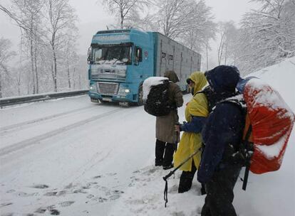 Un grupo de peregrinos deja pasar un camión en Ibañeta (Navarra), totalmente cubierto por la nieve.