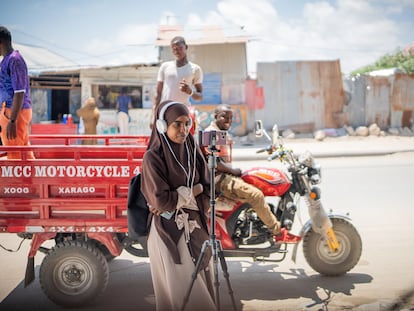 Una periodista del medio somalí Bilan, compuesto exclusivamente por mujeres, filma en una calle ante la mirada de varios hombres.
