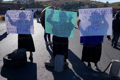 Mujeres sostienen carteles mientras bloquean una carretera durante una ceremonia en homenaje a las personas asesinadas en el pueblo de Chiquix, en Santa Catarina Ixtahuacan, Guatemala.