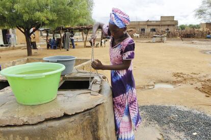 Mujer sacando agua del pozo a pulso.