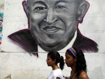 Dos mujeres caminan frente a un grafiti con la imagen del presidente venezolano Hugo Chávez en el centro de Caracas (Venezuela).