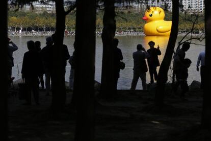 Turistas observan el pato de goma gigante, obra del artista Florentijn Hofman, que flota en las aguas del parque Siglo en Shanghái.